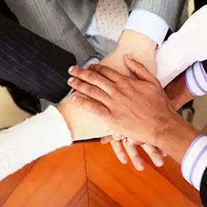 People showing unity and teamwork by stacking hands together - Vision Law