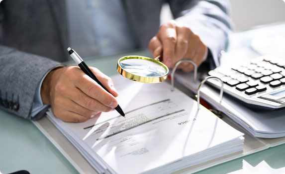 A person holding a magnifying glass over a document - Vision Law